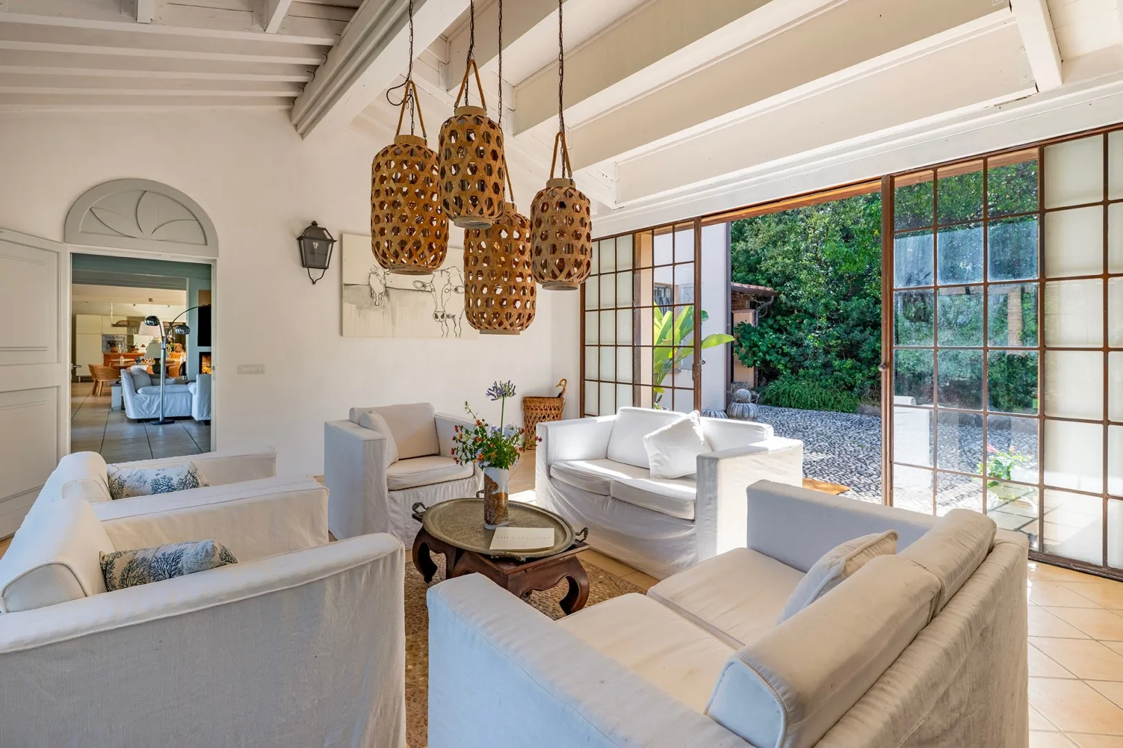Una sala luminosa con asientos blancos y grandes ventanas con vistas a la vegetación.