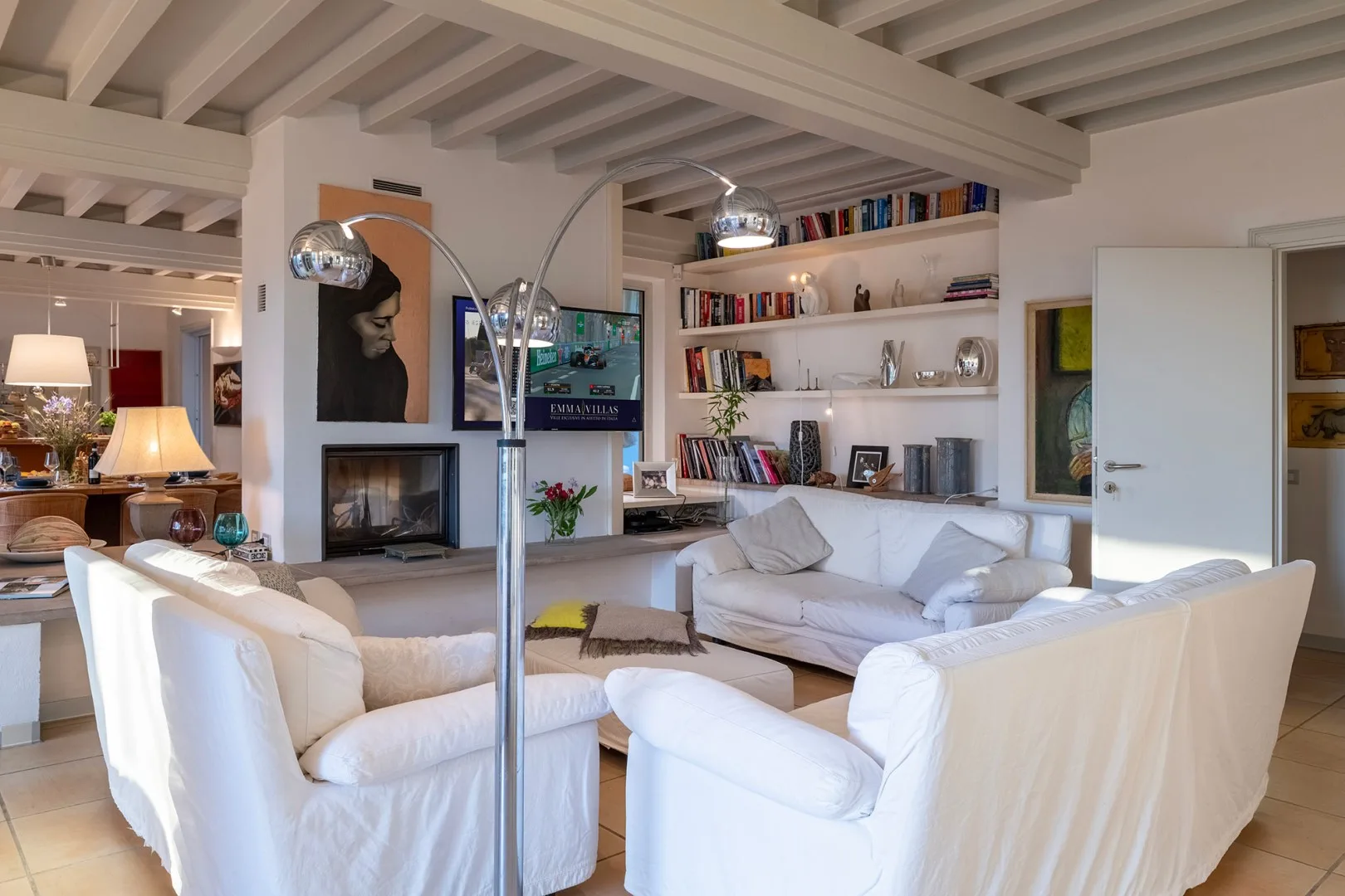 Sala de estar con asientos blancos, una chimenea y estanterías empotradas.