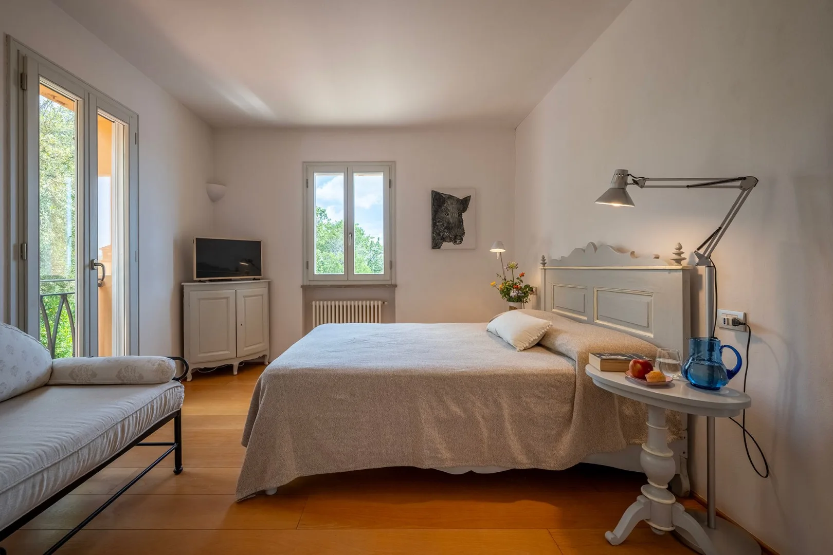 Un dormitorio con una cama, una ventana y una pequeña zona de estar.