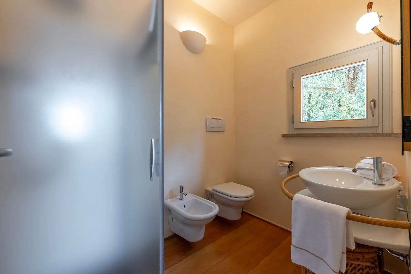 Un baño con lavabo, inodoro, bidé y una ventana.