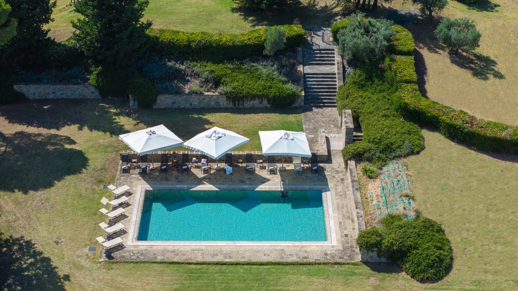 Una piscina al aire libre está junto a un jardín paisajístico y unos escalones.