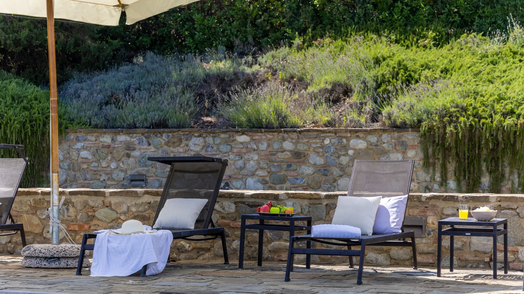Una zona de estar al aire libre con sillones junto a un muro de piedra.