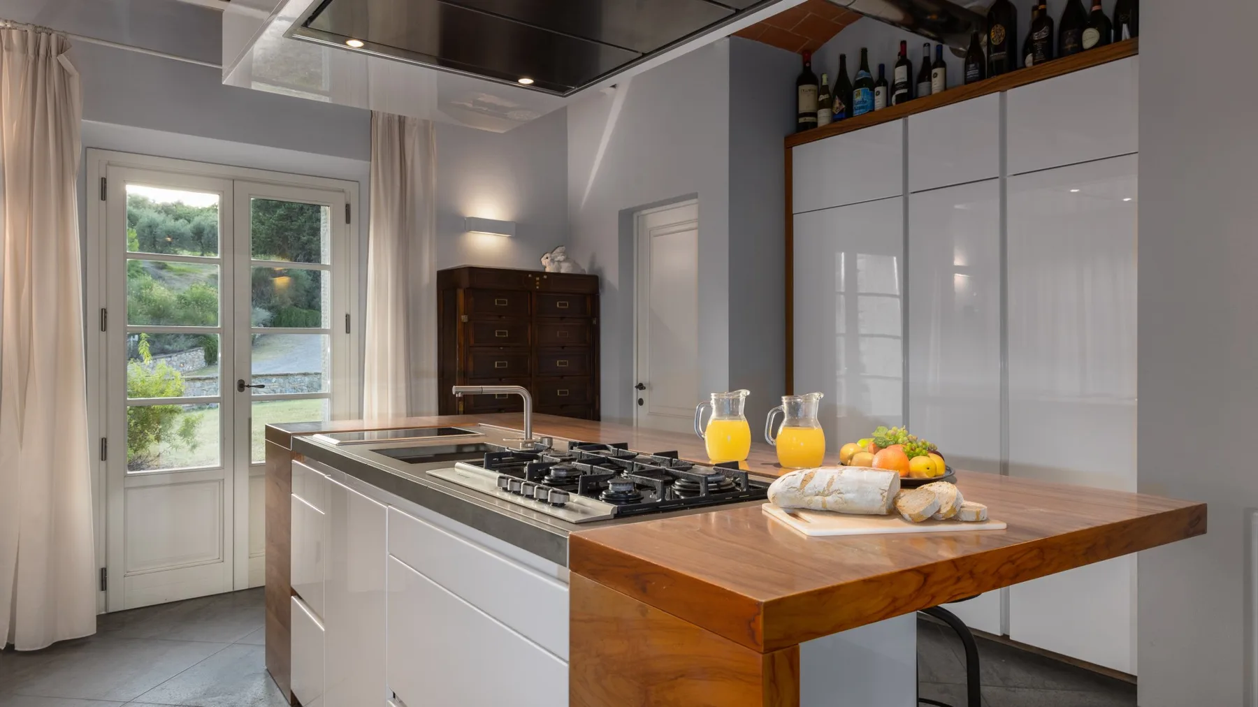 Una cocina luminosa con una isla grande, una placa de cocción y una encimera de madera.