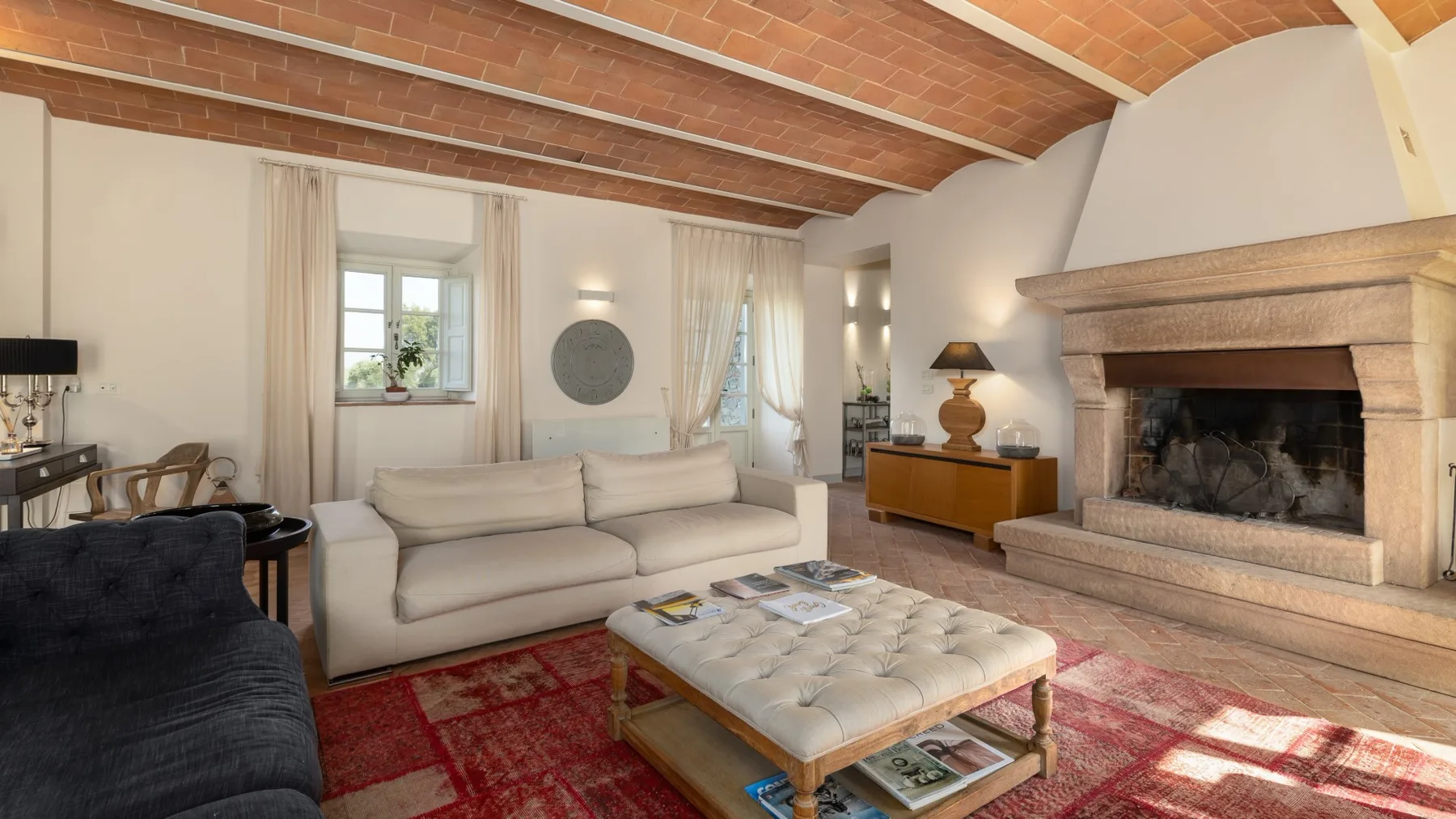 Una sala de estar con asientos claros, una mesa de centro y una chimenea bajo un techo de ladrillo.