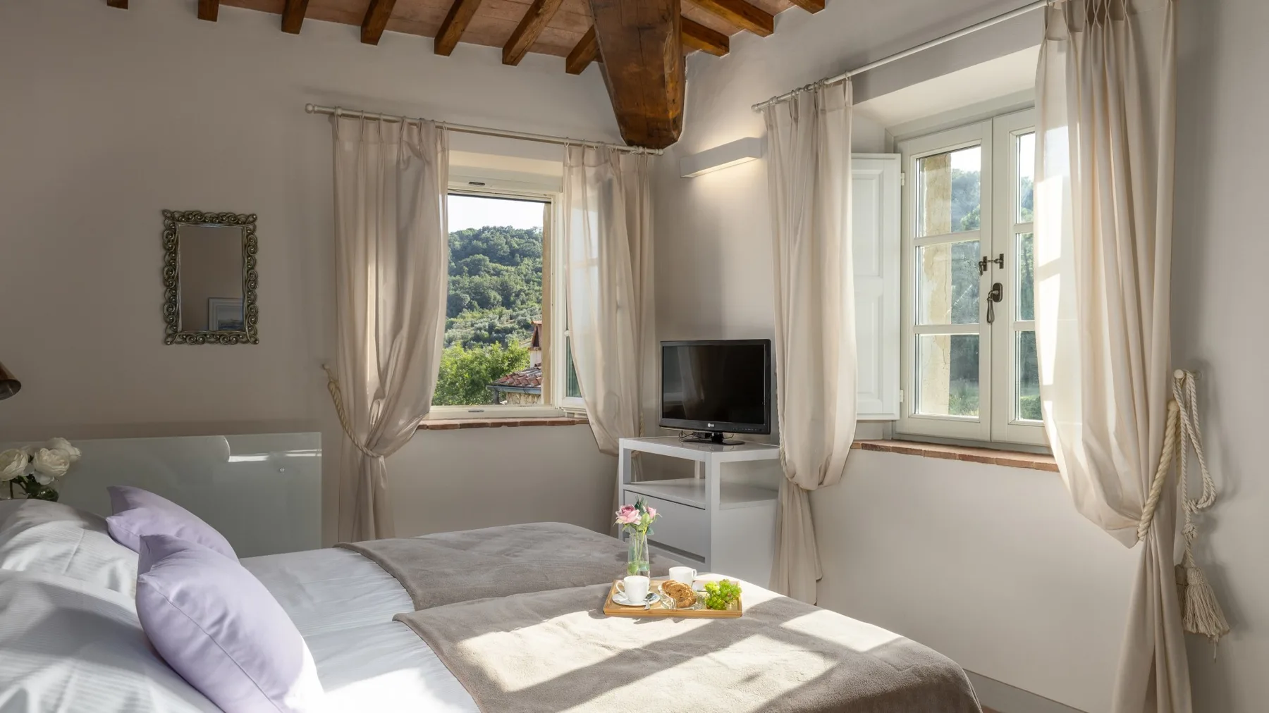 Un dormitorio con una cama, dos ventanas y un televisor.