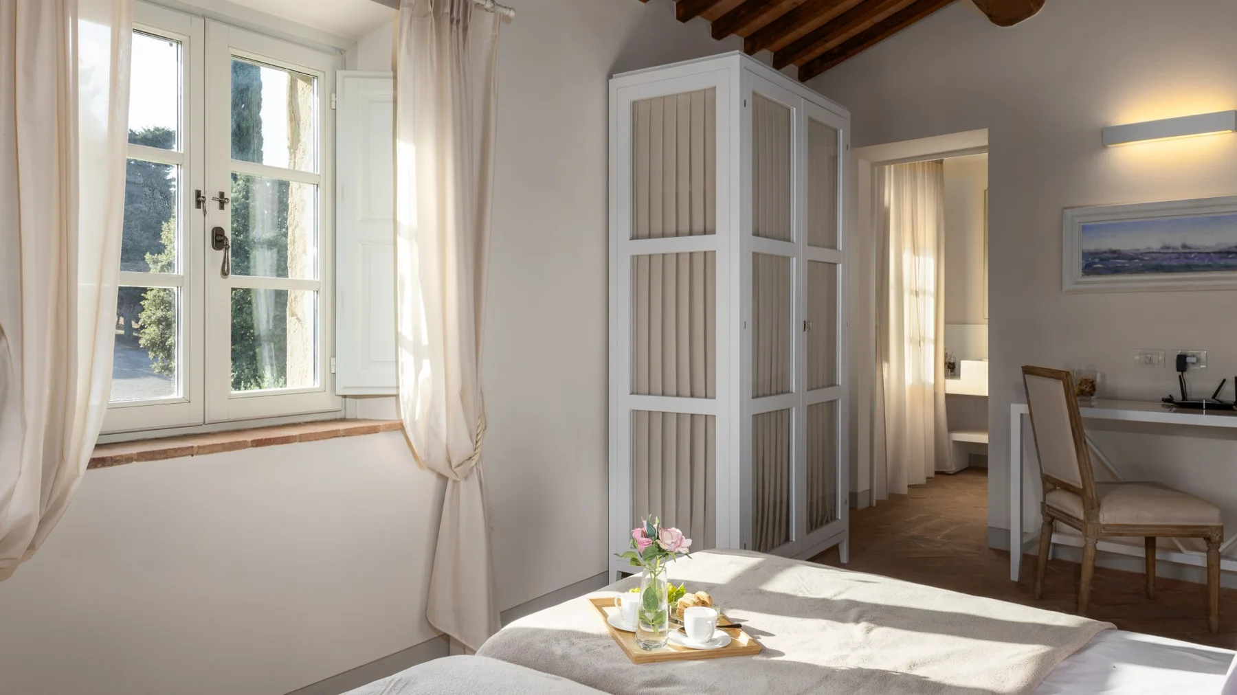 Un dormitorio luminoso con una ventana grande y una cama en primer plano.