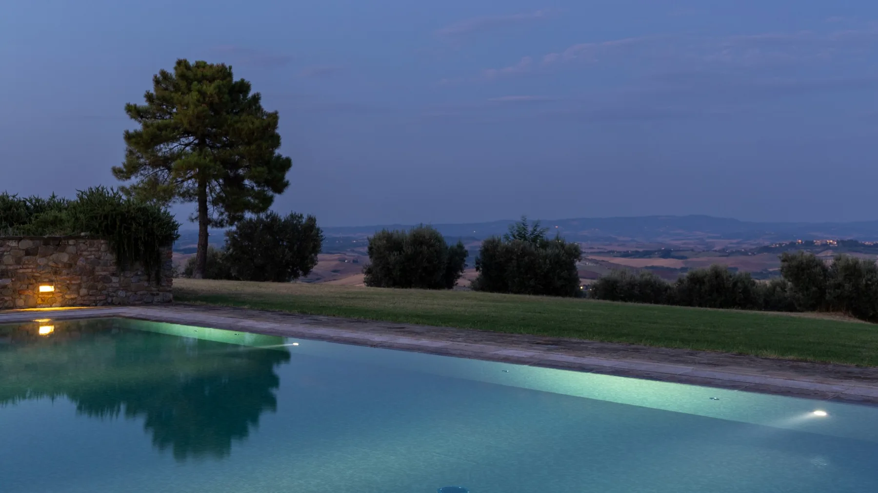 Una piscina al aire libre da a un amplio paisaje al anochecer.