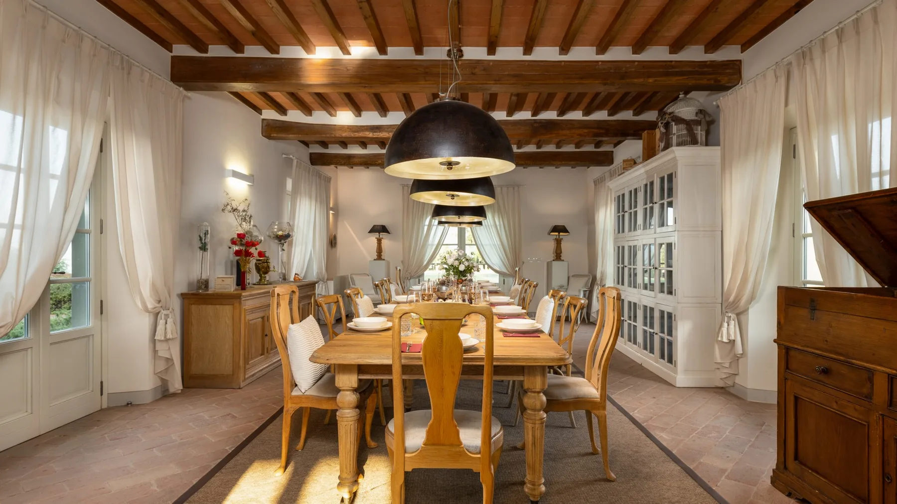 Comedor con una larga mesa de madera bajo vigas de techo expuestas.