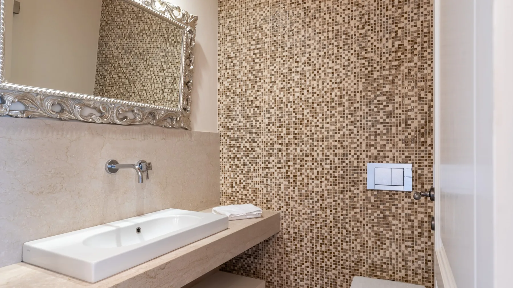 Un lavabo de baño con una pila rectangular y una pared de azulejos estampados.