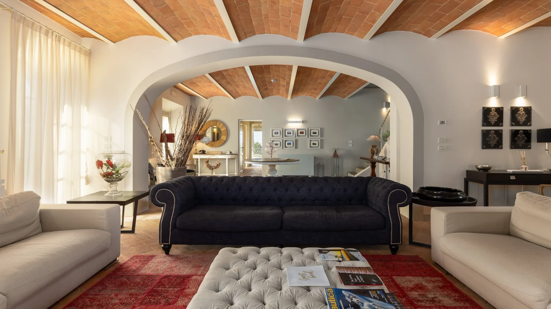Una sala de estar con asientos oscuros bajo un arco y vigas de madera expuestas en el techo.