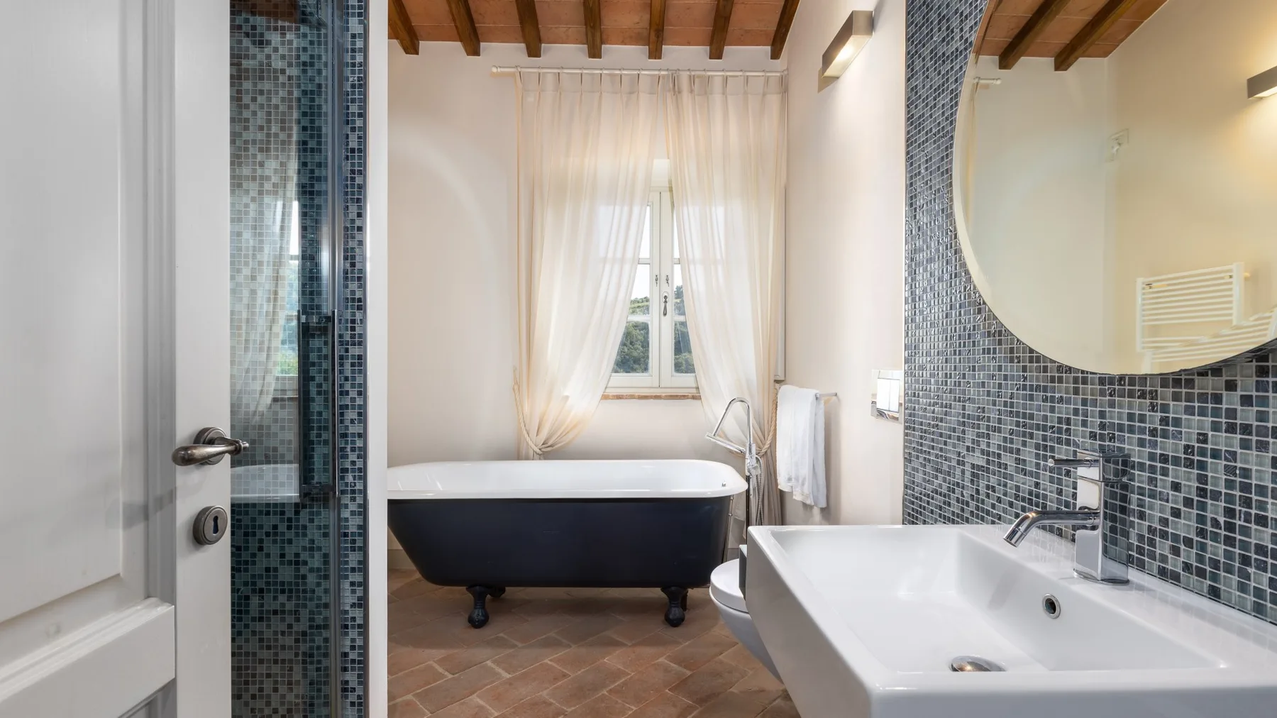 Un baño luminoso con una bañera exenta y un lavabo.