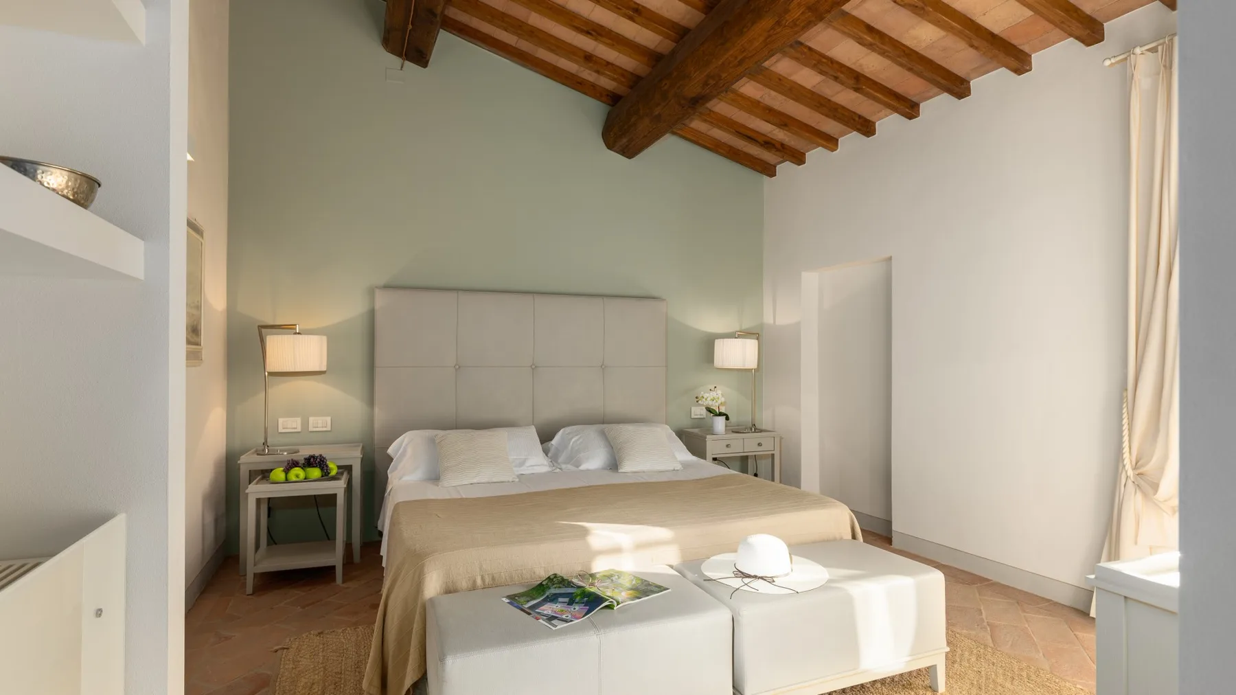 Un dormitorio con una cama grande, mesitas de noche y vigas de madera a la vista.
