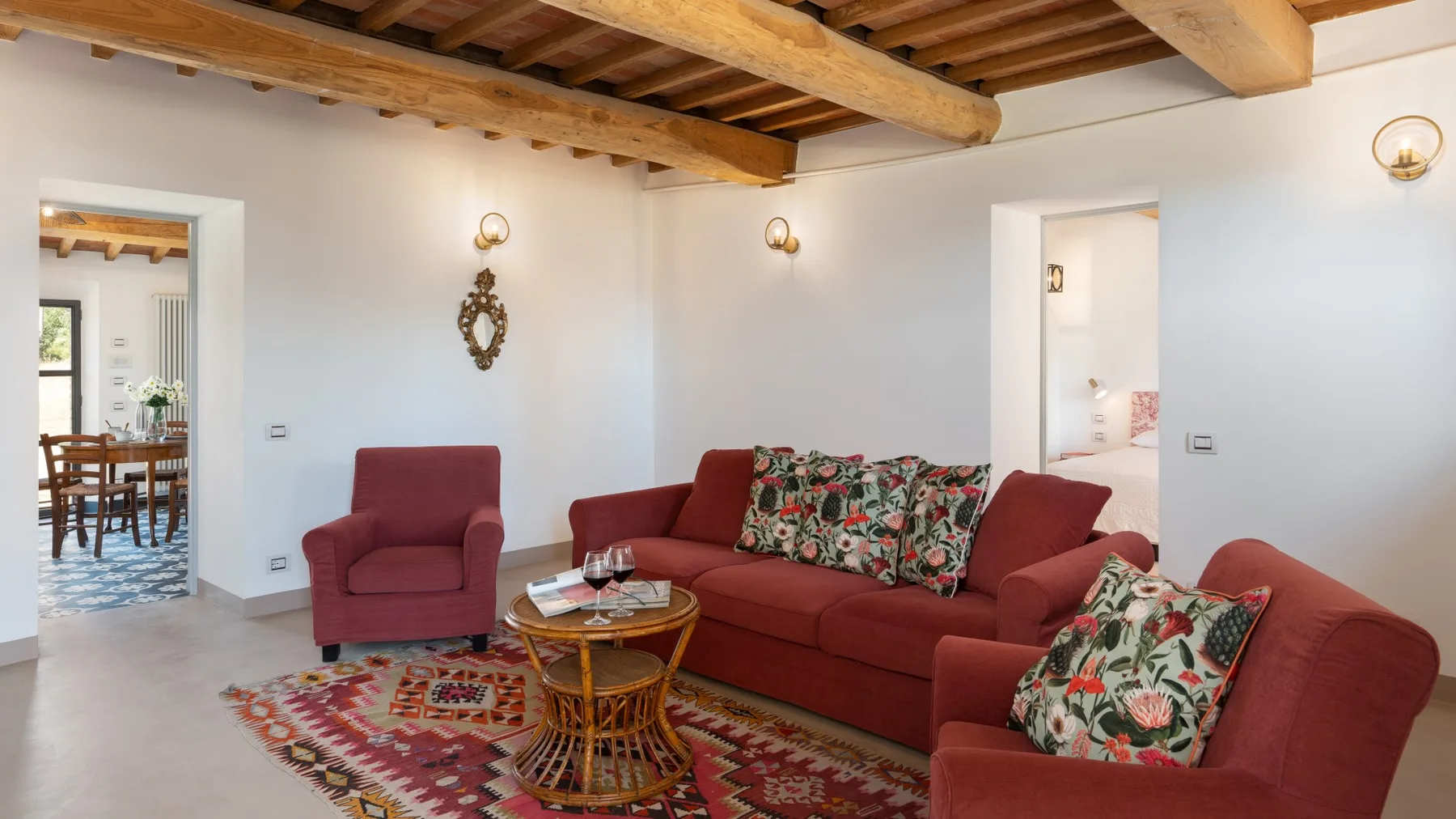 A living room with red seating, patterned cushions, and a wooden ceiling.