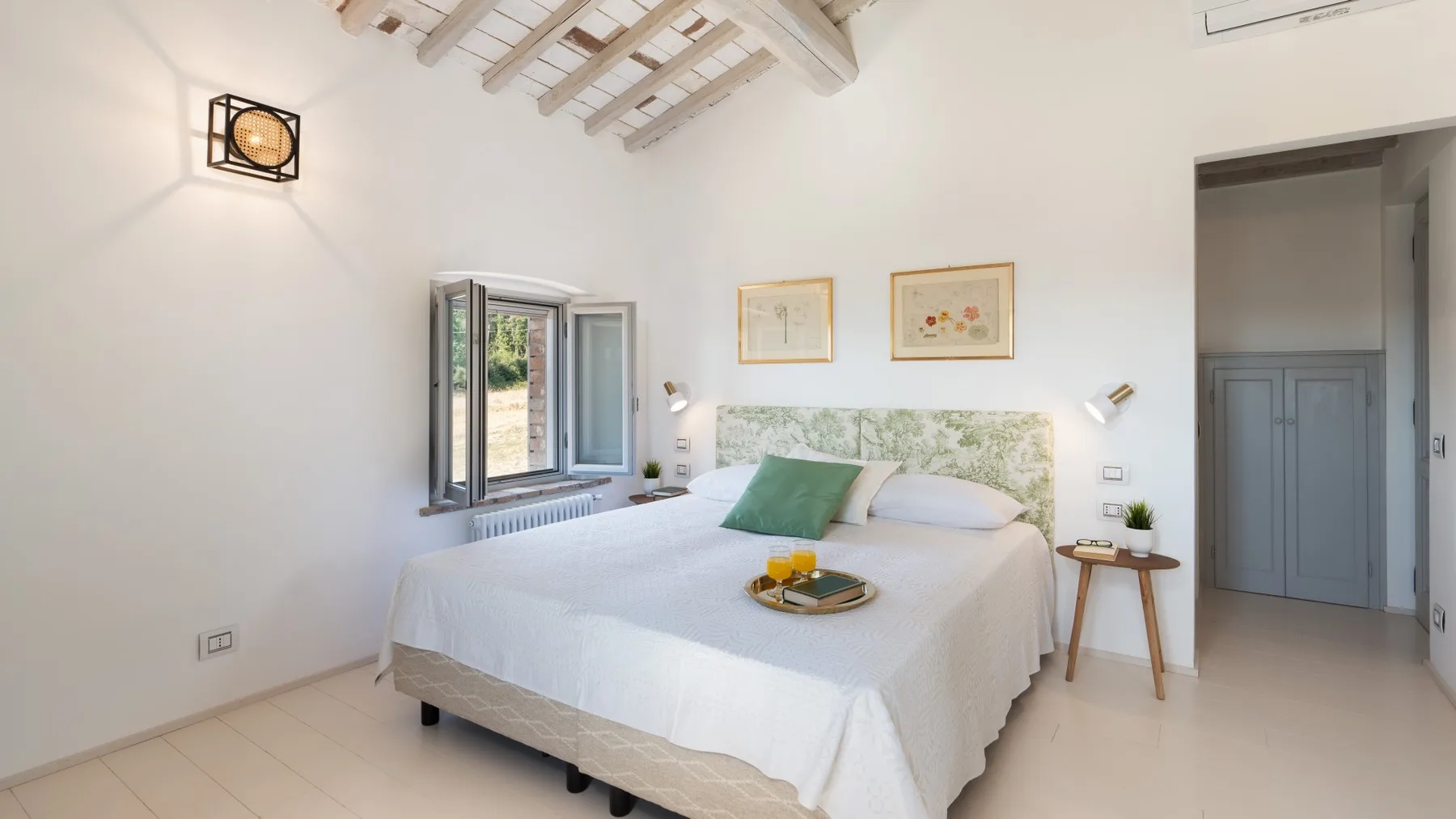 A bright bedroom with a neatly made bed and an open window.