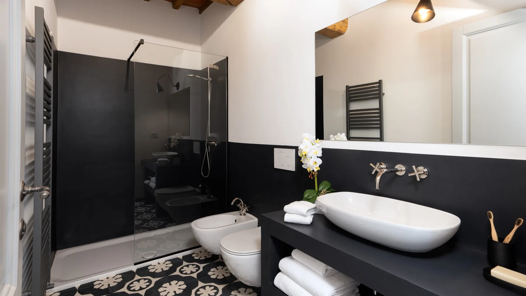 A modern bathroom with a dark vanity and a glass-enclosed shower.