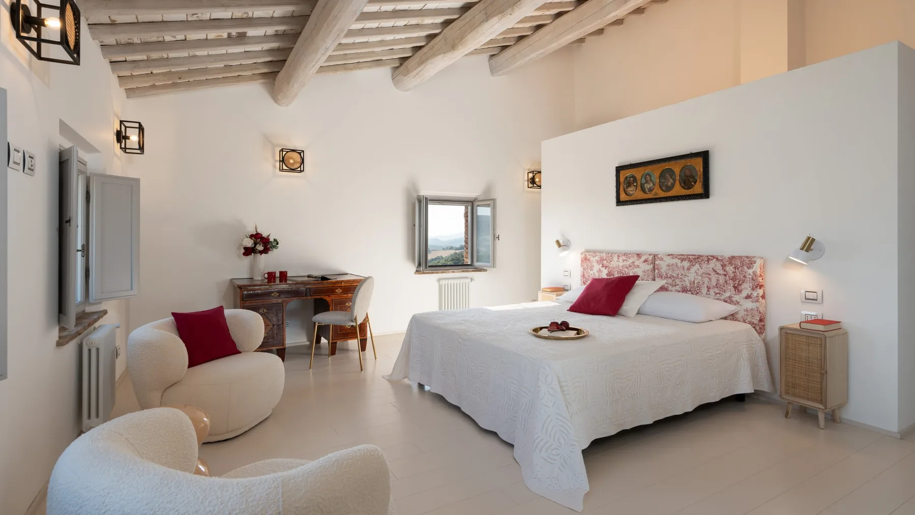 A bedroom with a double bed, a small dining table, and a seating area.