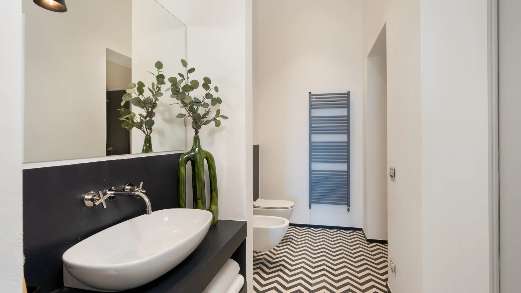 A modern bathroom with a vessel sink, mirror, and patterned floor.