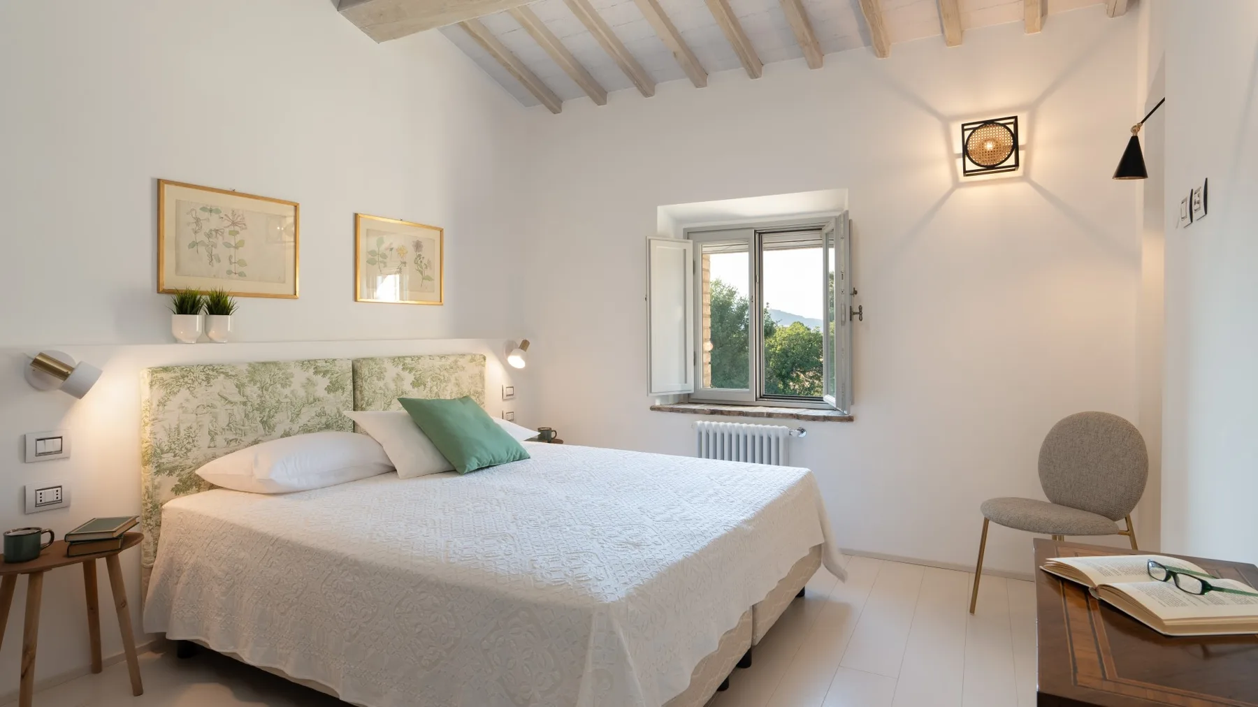 A bright bedroom with a bed, a window, and a chair.