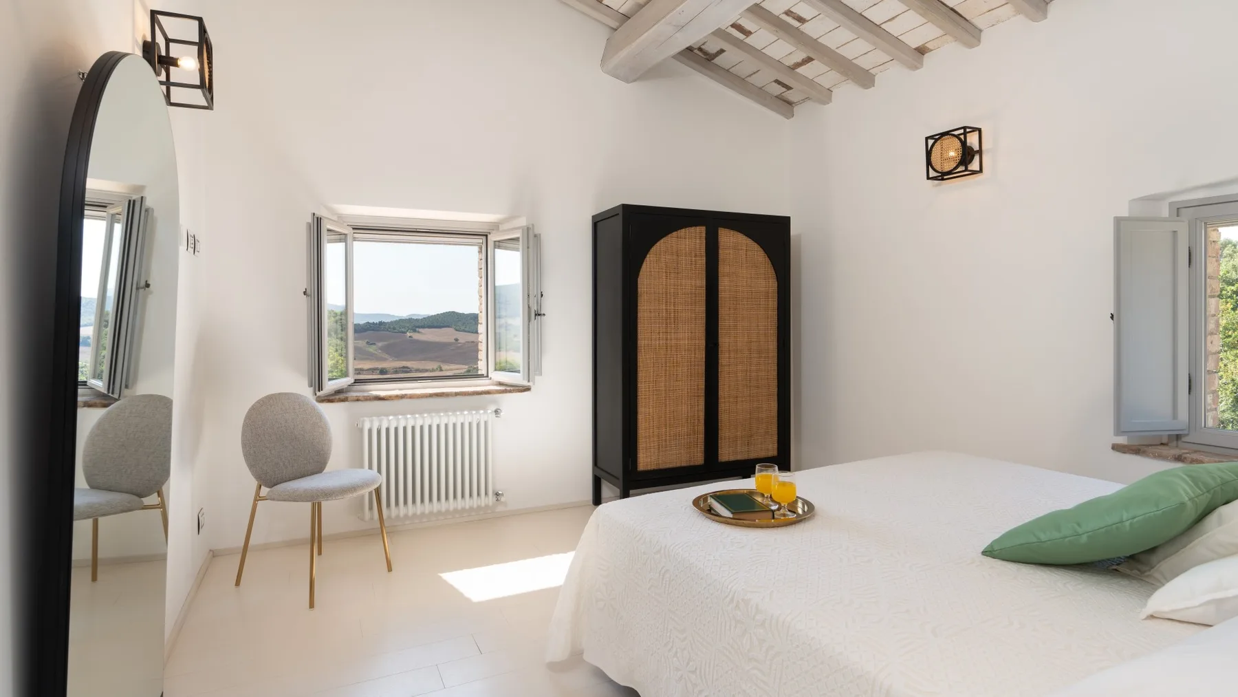 A bright bedroom with a white bed, a chair, and a wardrobe.