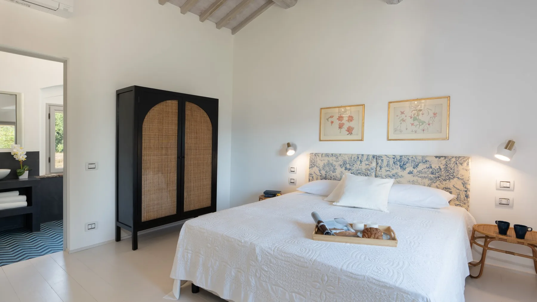 A bright bedroom with a large bed and a dark wardrobe.