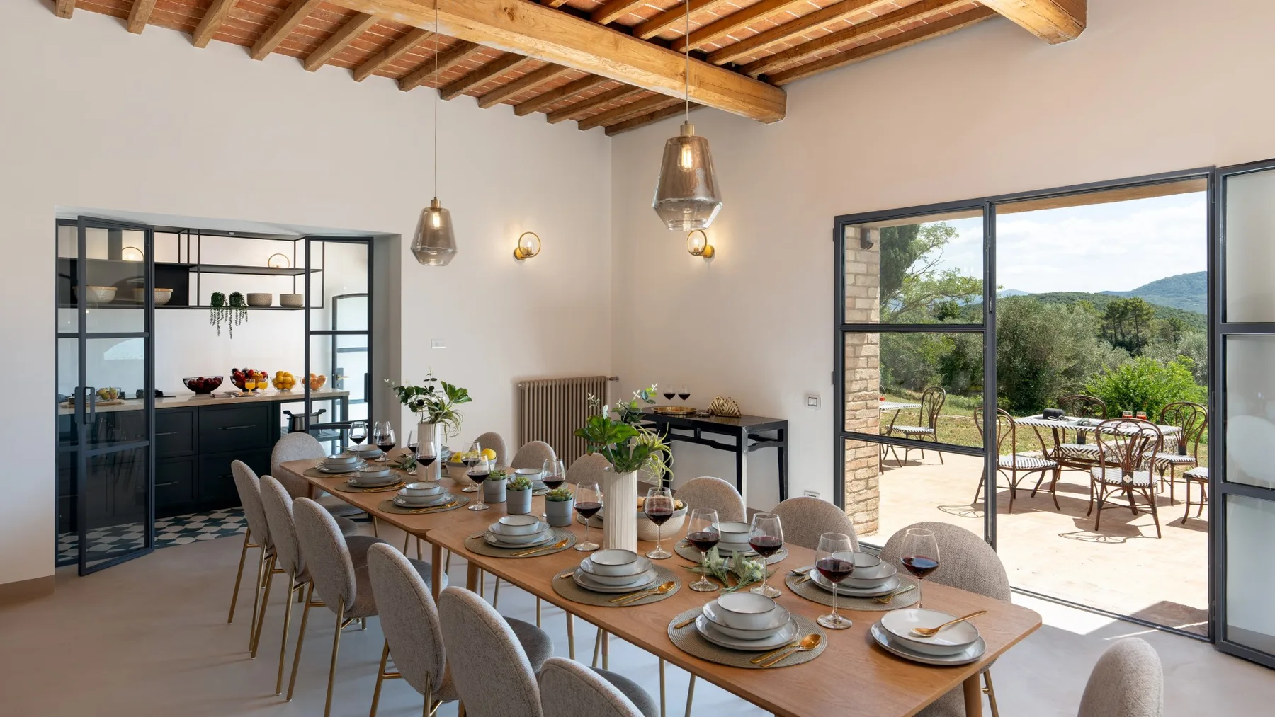 A dining room with a long table set for a meal beside large patio doors.