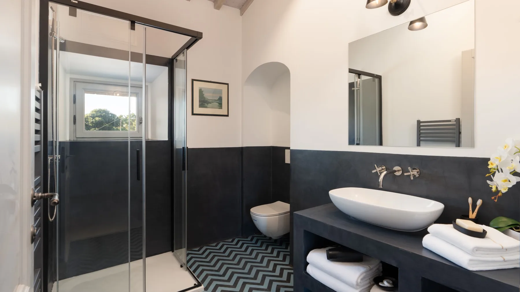 A modern bathroom features a glass shower and a white vessel sink.