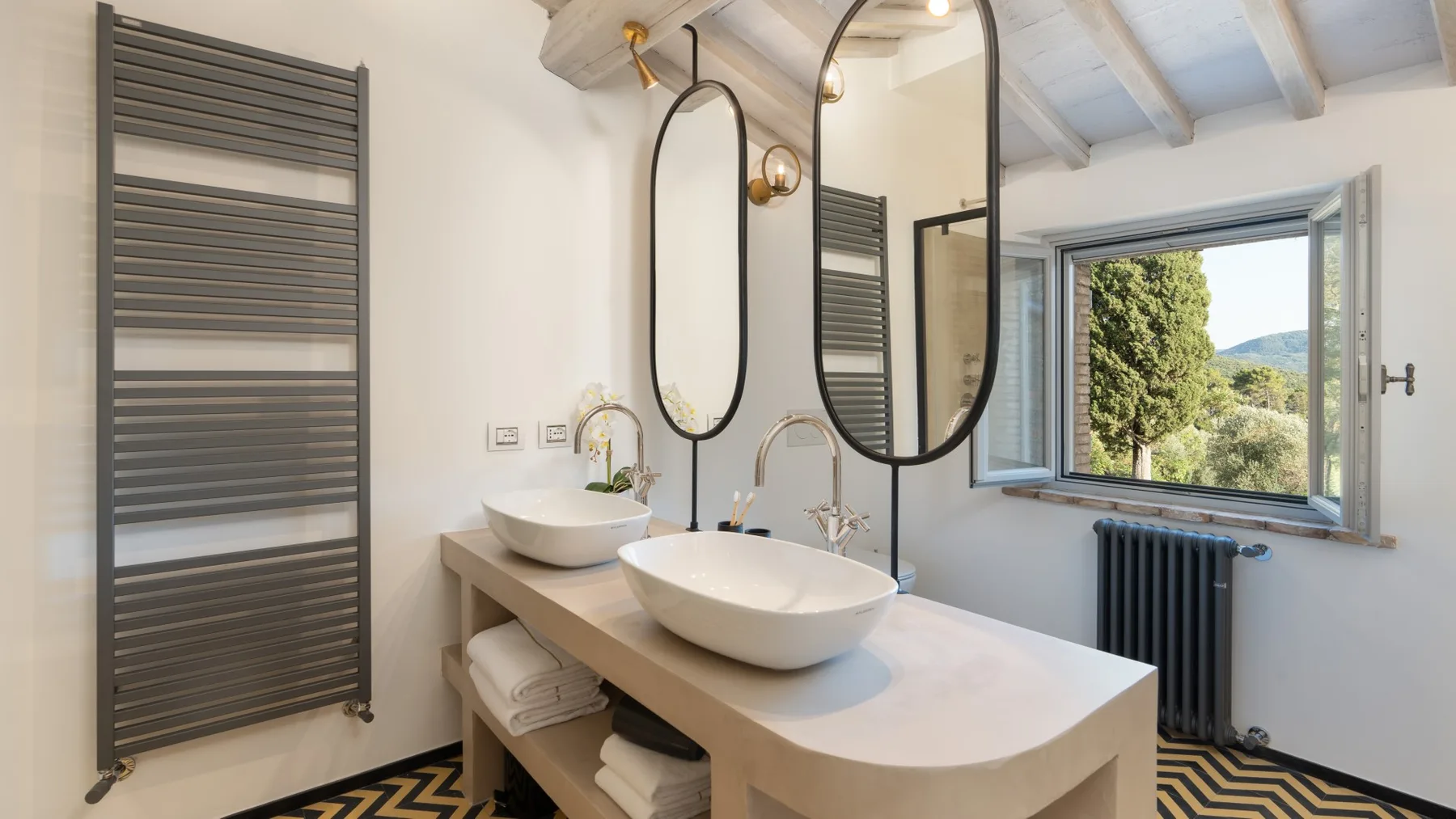 A bright bathroom with a long vanity, vessel sinks, and an open window.