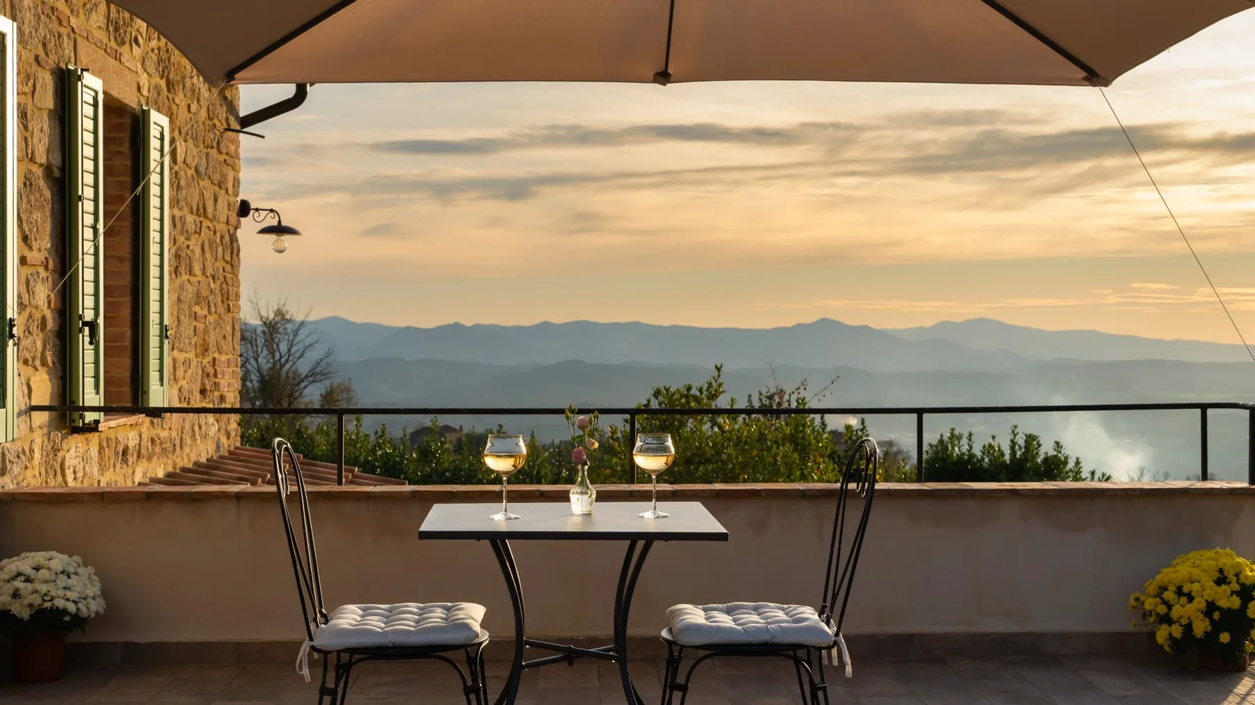 Una zona de comedor en una terraza ofrece vistas a una cordillera al atardecer.