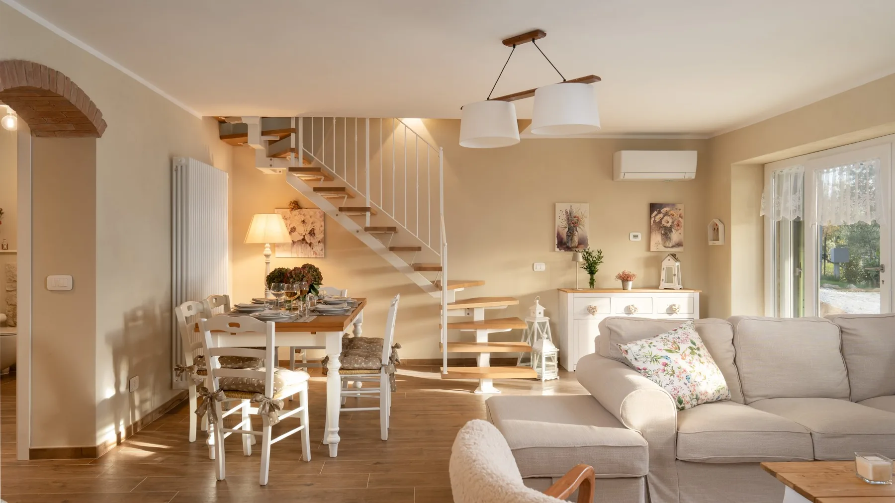Una luminosa sala de estar con mesa de comedor y escalera.