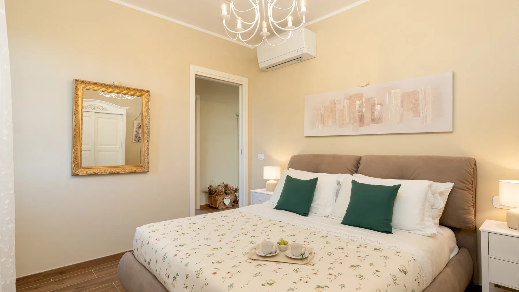 Un dormitorio con una cama grande, ropa de cama con estampado floral y cojines verdes.