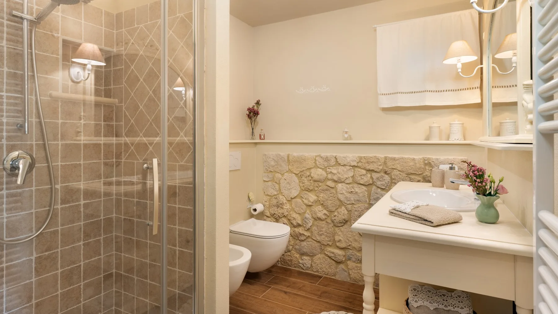 Un baño con ducha de vidrio, pared decorativa de piedra y tocador.