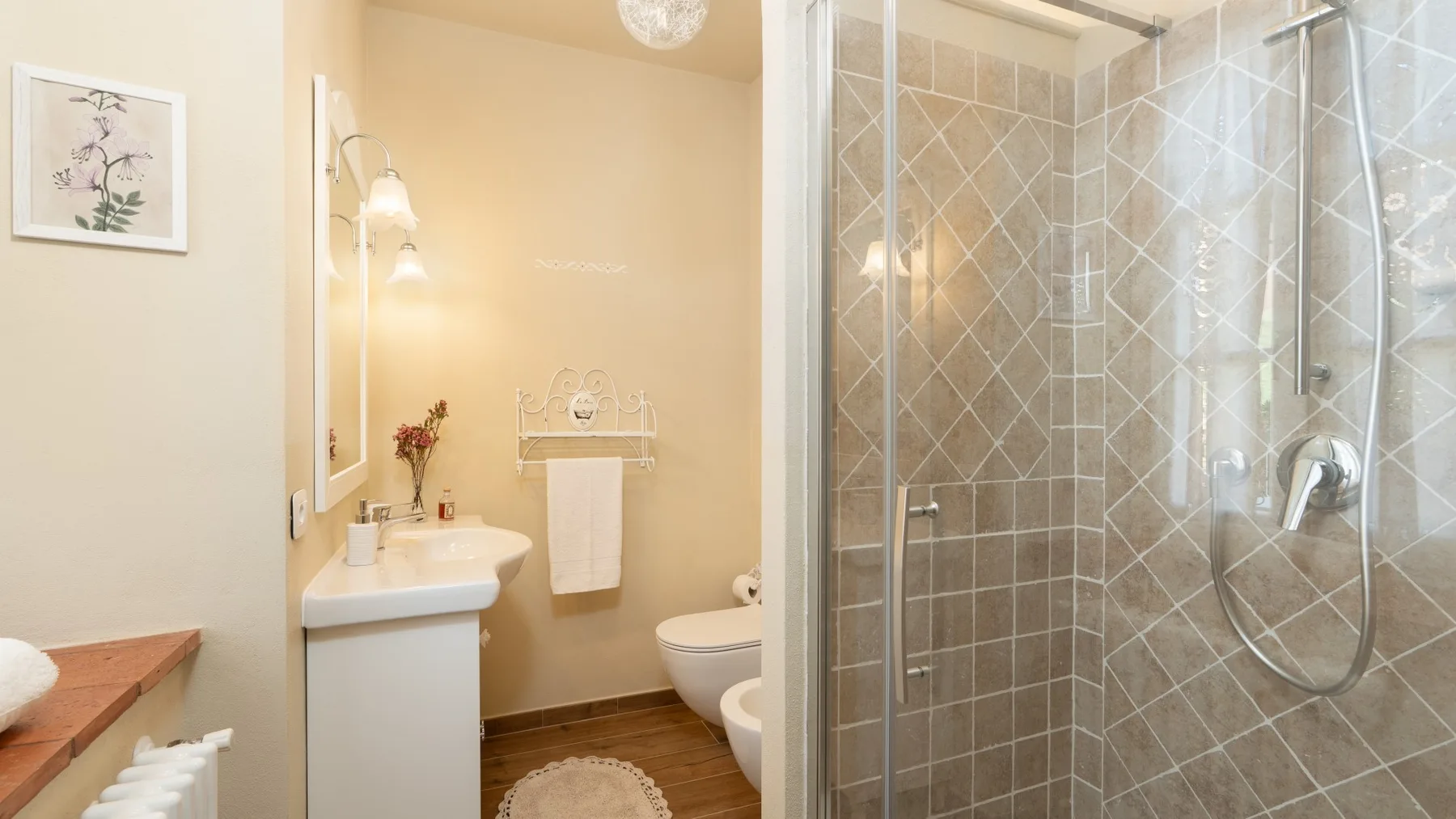 Un baño con un lavabo junto a una ducha con mampara de vidrio.