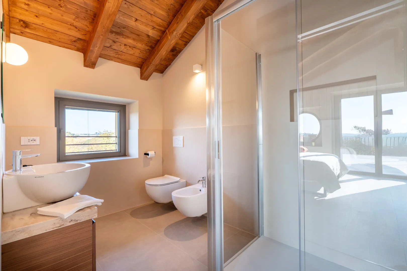 A bathroom with a vessel sink, toilet, and glass shower enclosure.