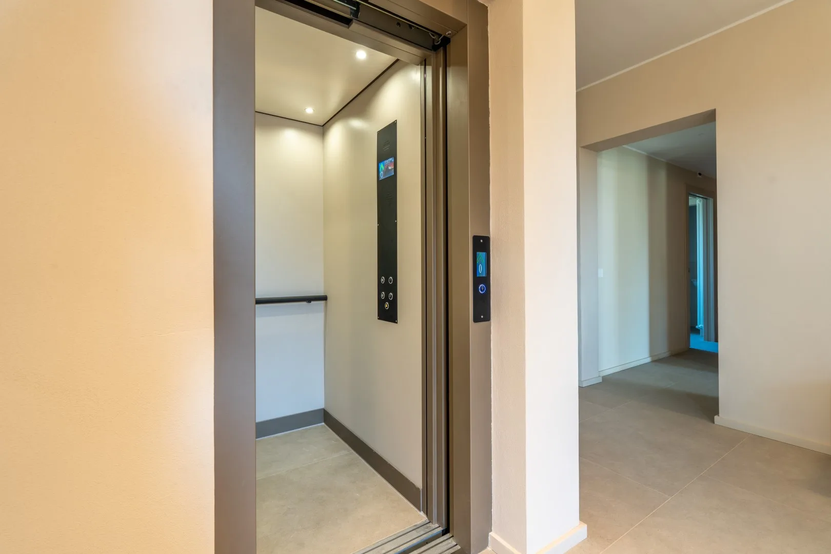 An open elevator beside a doorway leading into a hallway.