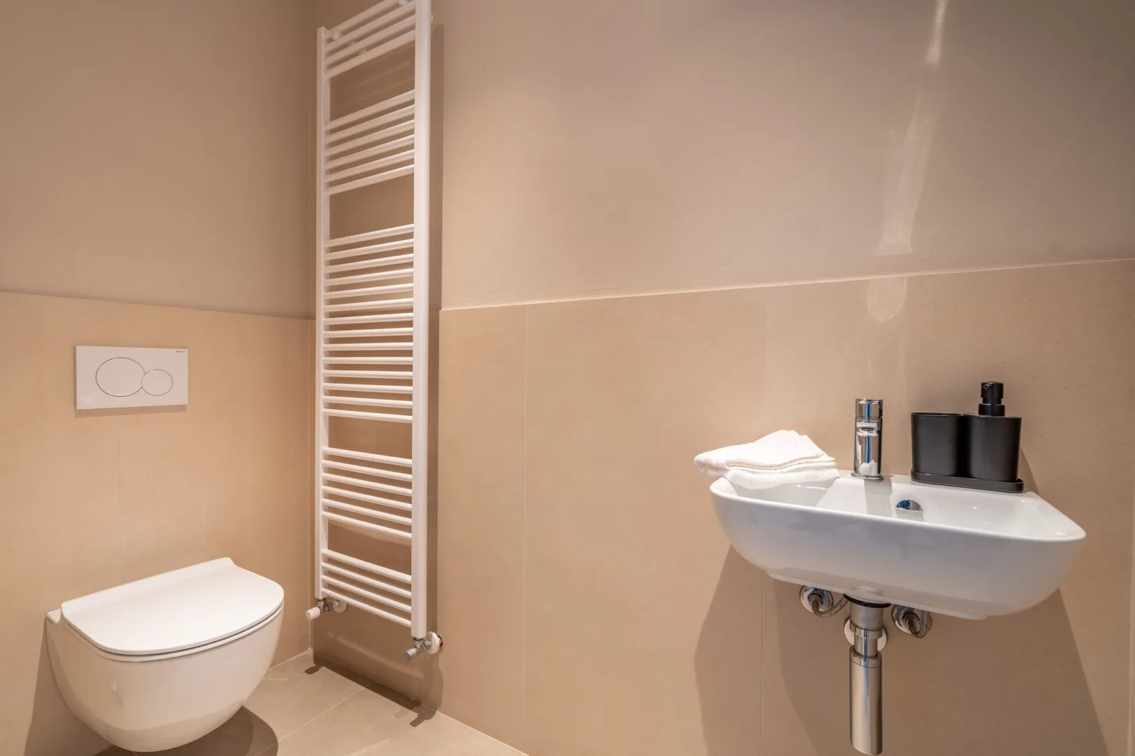 A bathroom with a wall-mounted sink and toilet.