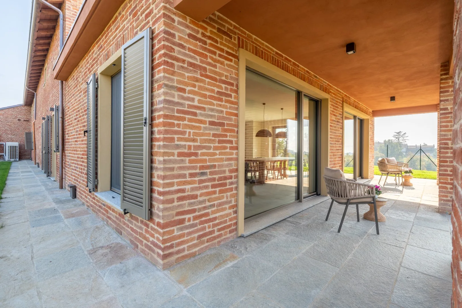 A covered brick patio with sliding glass doors and outdoor seating.