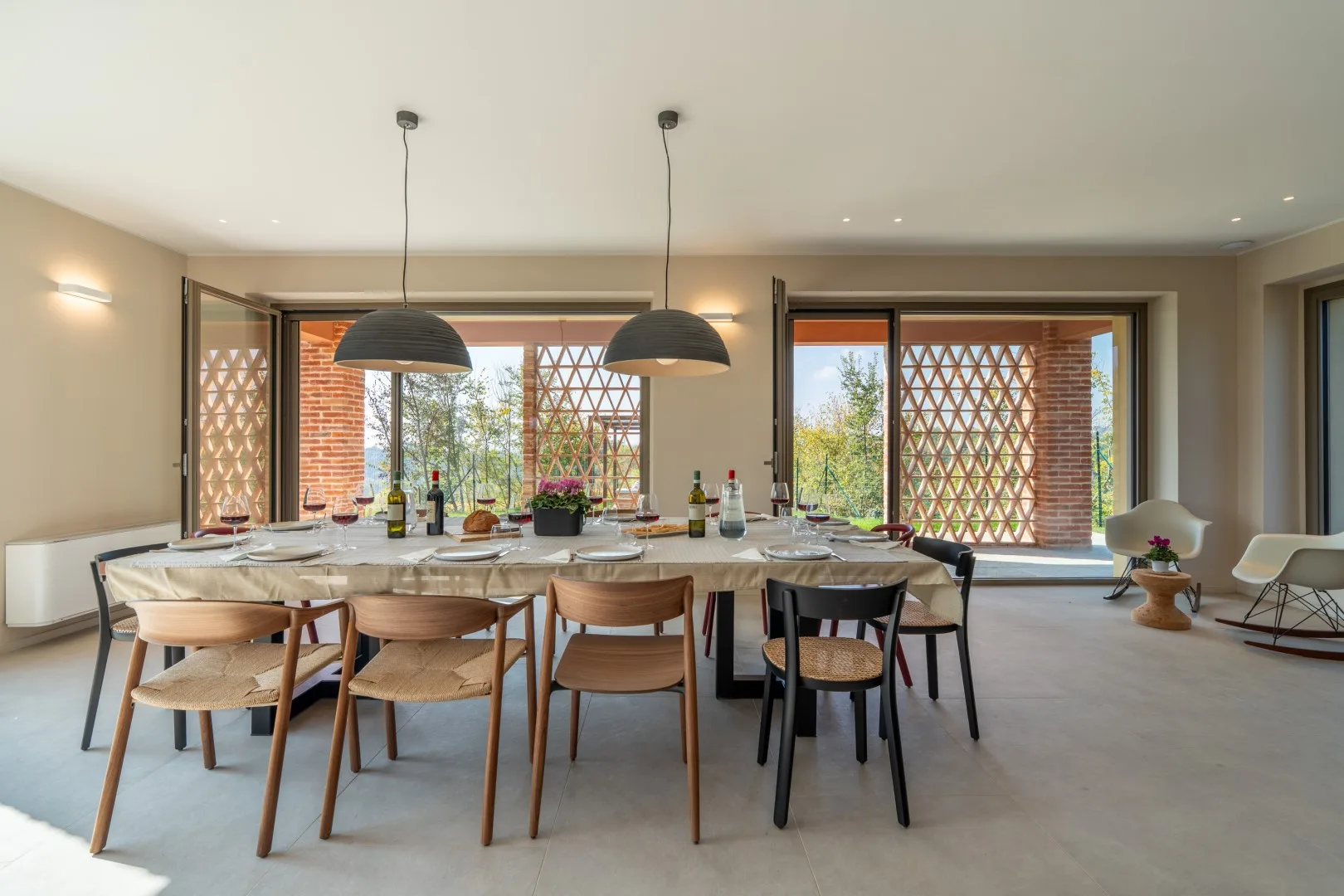 A dining area with a long table and large windows.