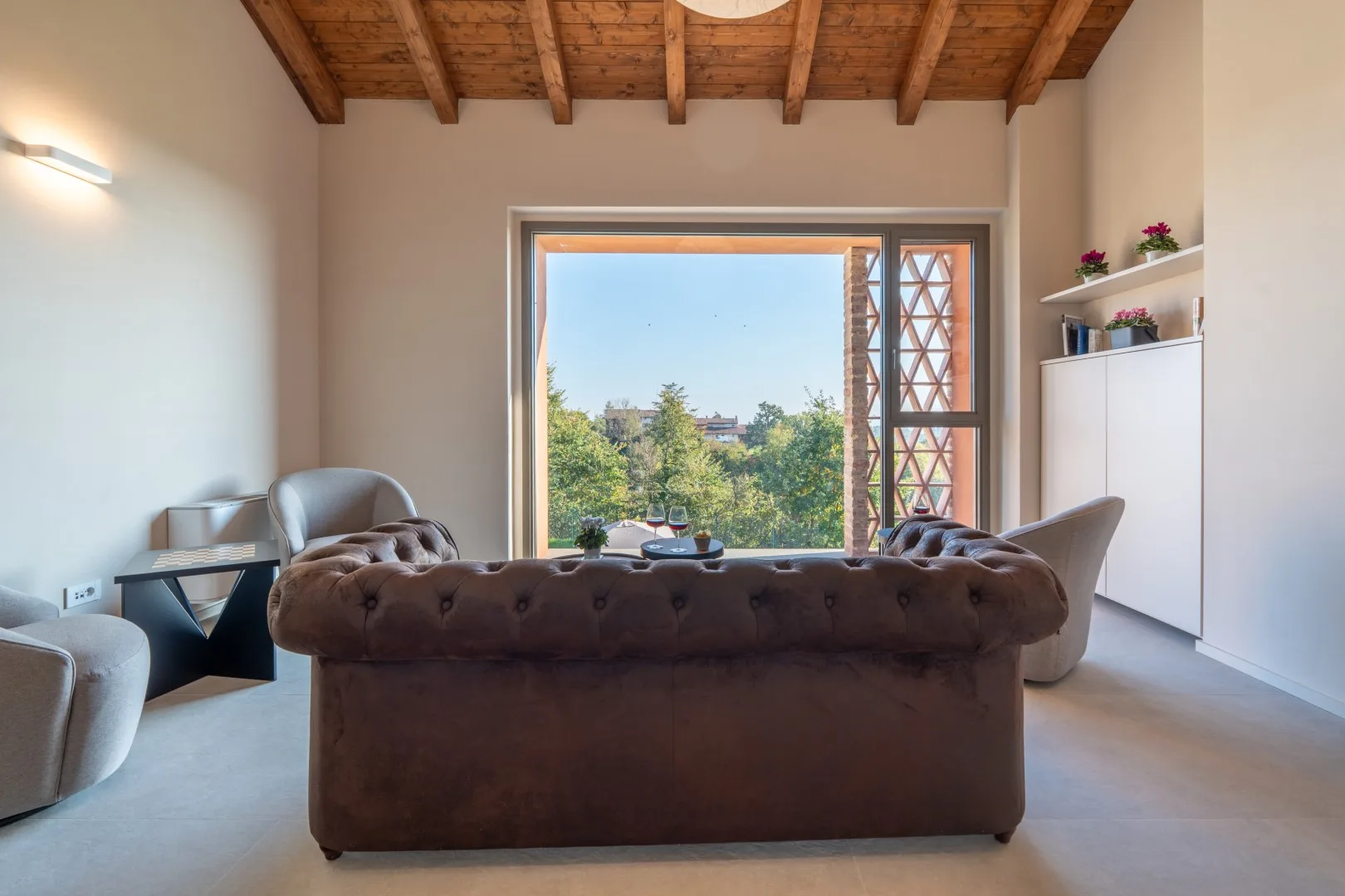 A living room with seating facing a large window overlooking greenery.