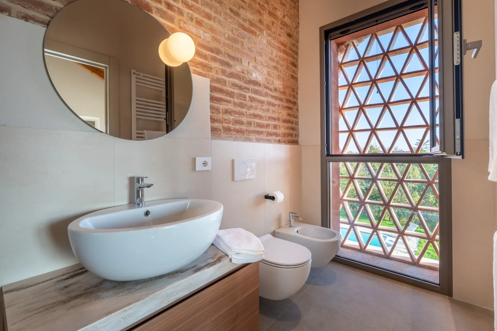 A bathroom with a vessel sink, toilet, and large window.