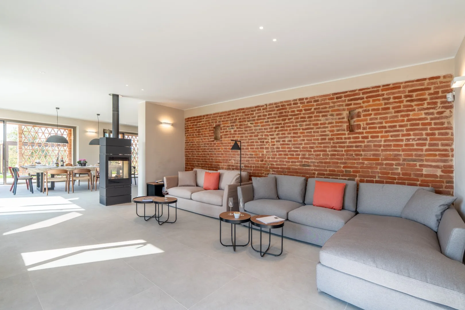 A bright living room with gray seating and an exposed brick wall.