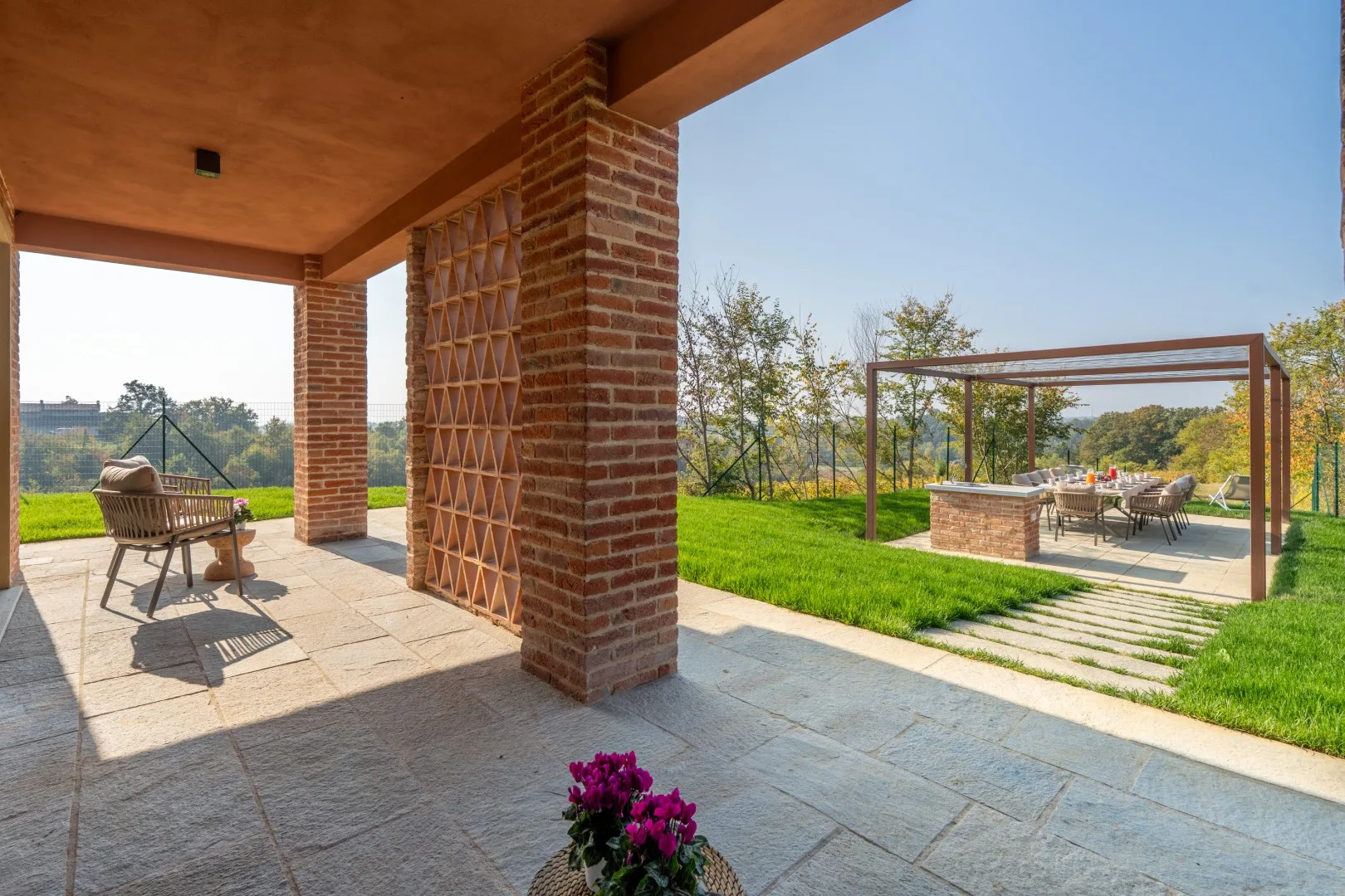 A covered patio opens onto a lawn and an outdoor dining area.