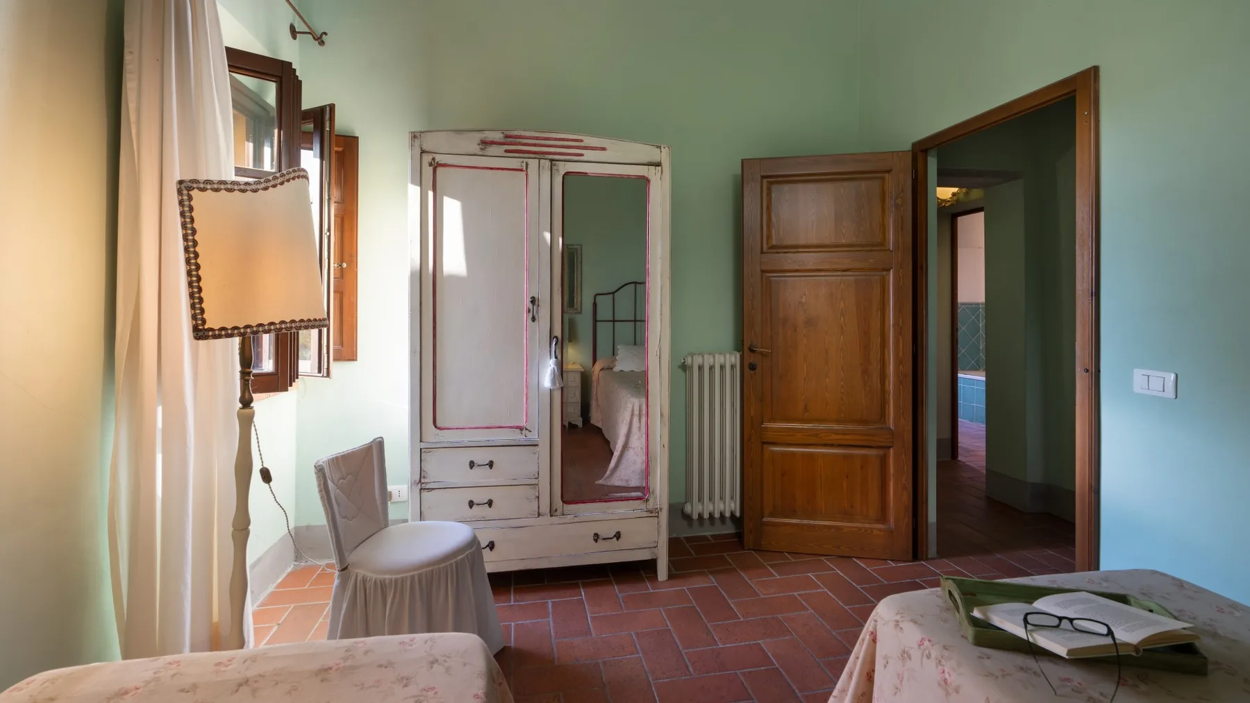 Un dormitorio con un armario, un radiador y una puerta de madera abierta.