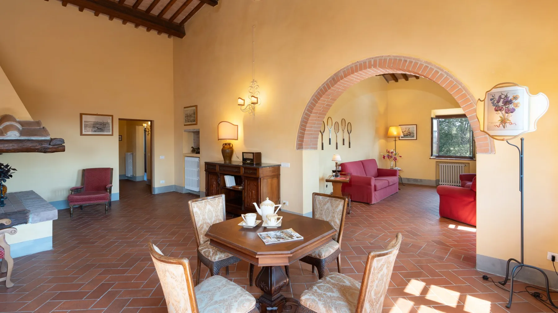 Una sala y comedor de tonos cálidos con una mesa bajo un arco.