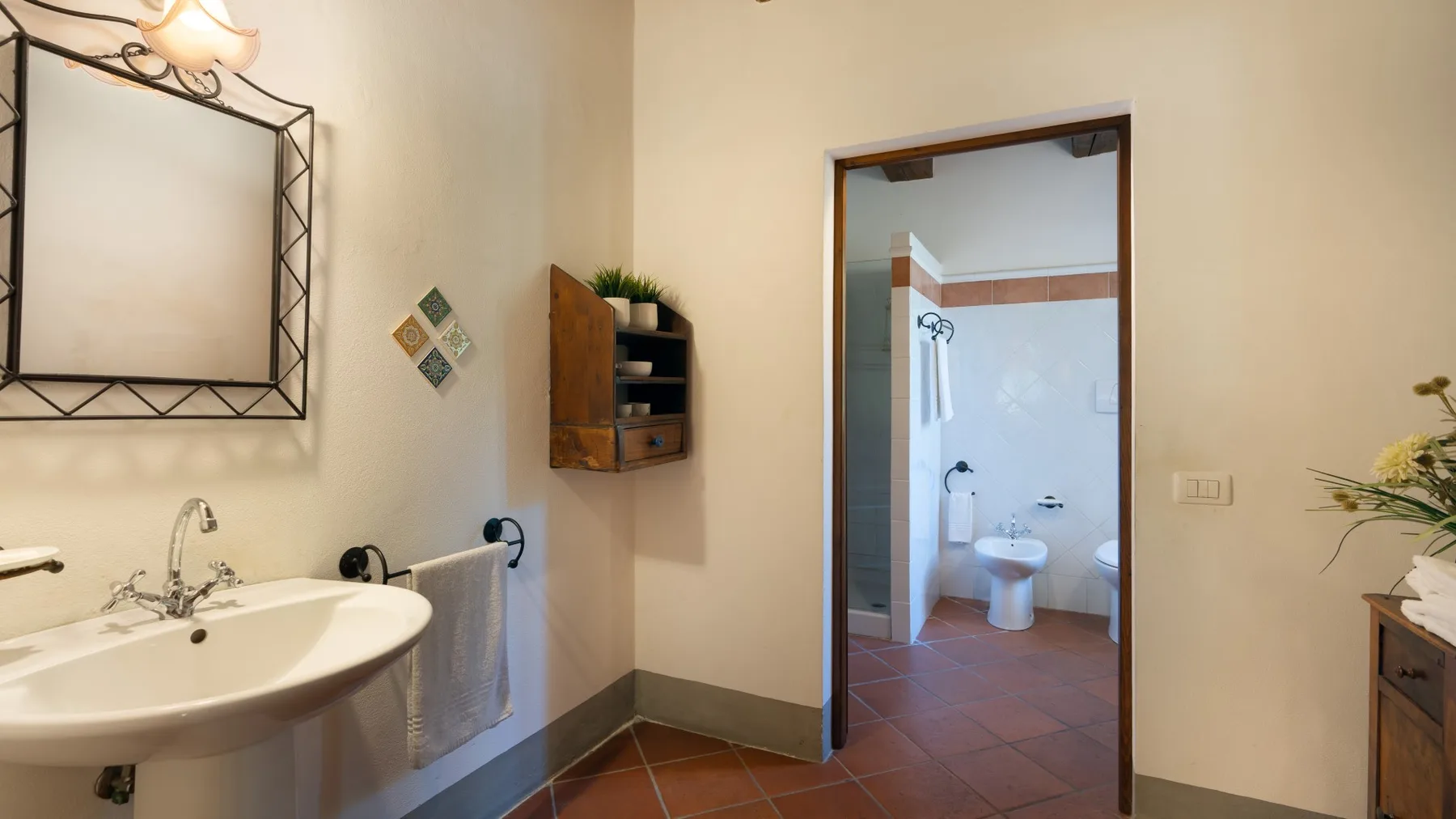 Un baño con lavabo y una vista a un espacio alicatado con inodoro y ducha.