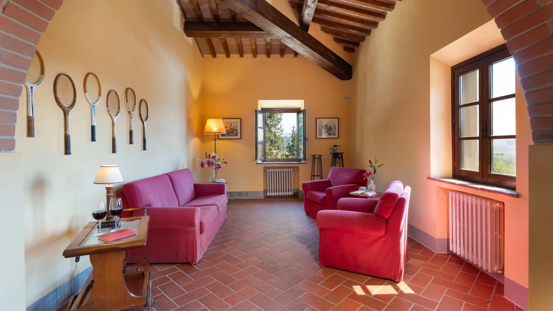 Una cálida sala de estar con asientos rojos, vigas expuestas y ventanas grandes.