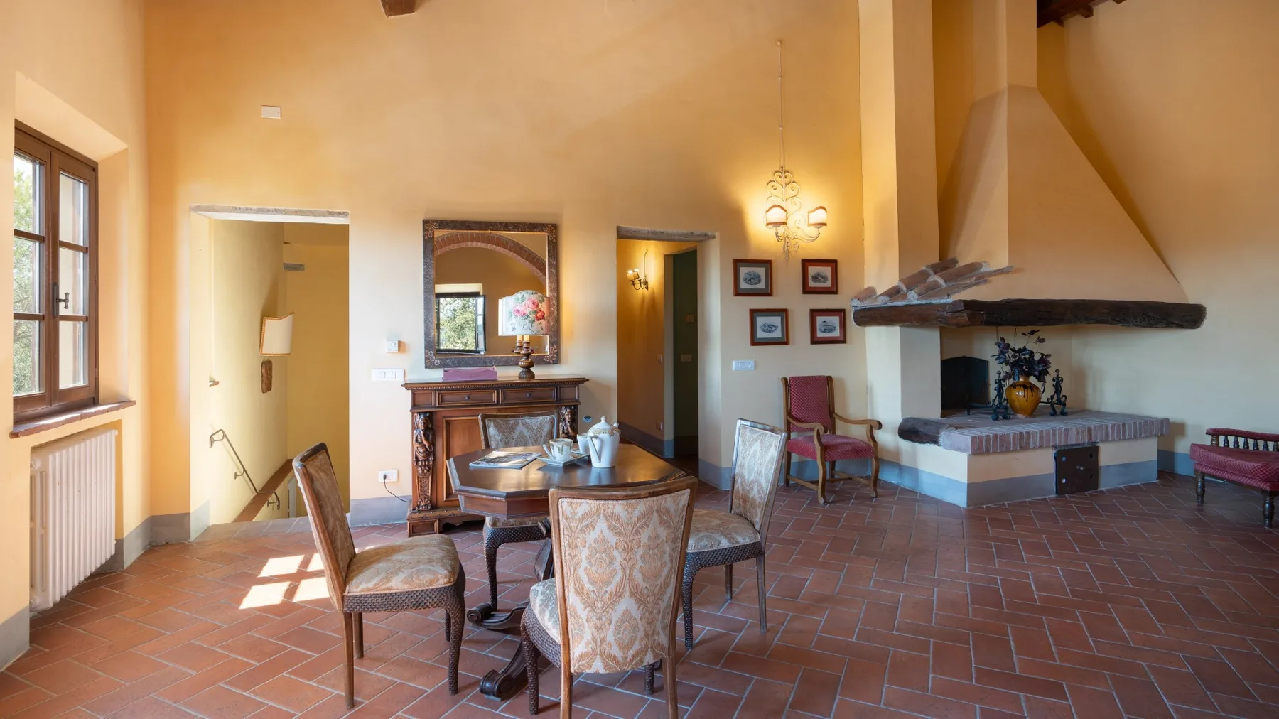 Una sala de estar en tonos cálidos con asientos, una chimenea y suelo de terracota.