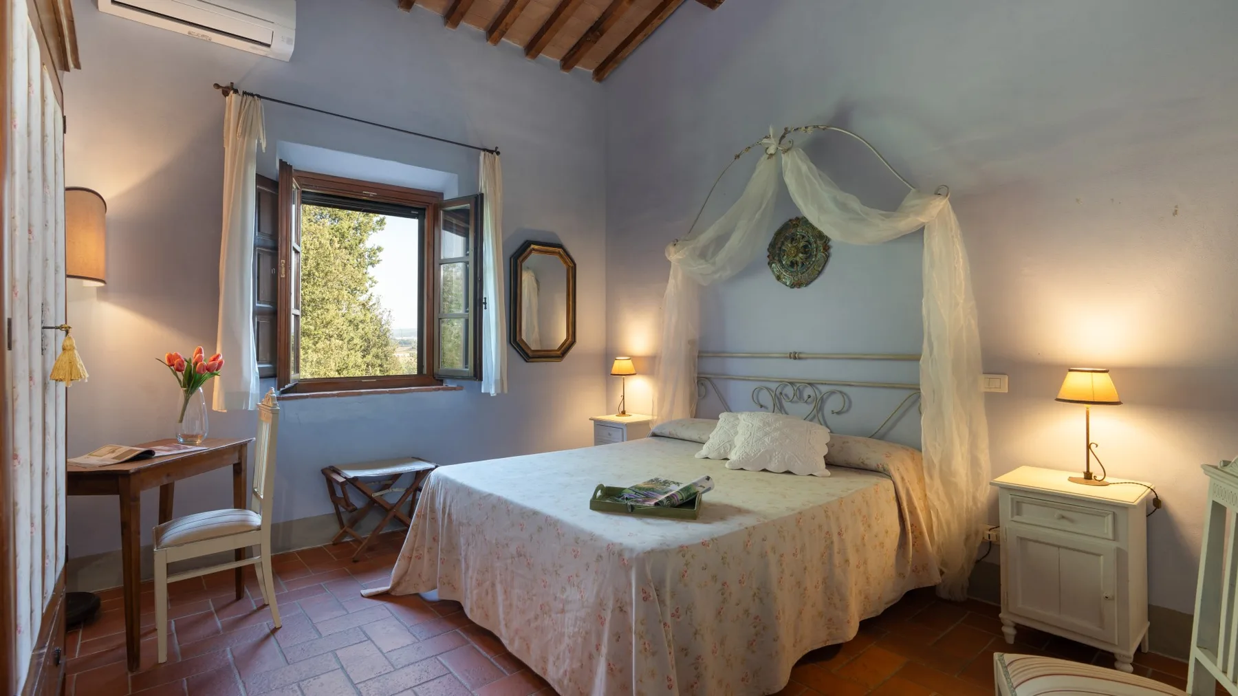 Un dormitorio con cama con dosel, una ventana abierta y lámparas de noche.