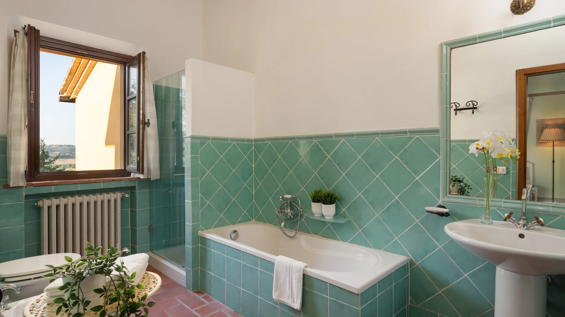 Un baño con bañera, lavabo y una ventana abierta.