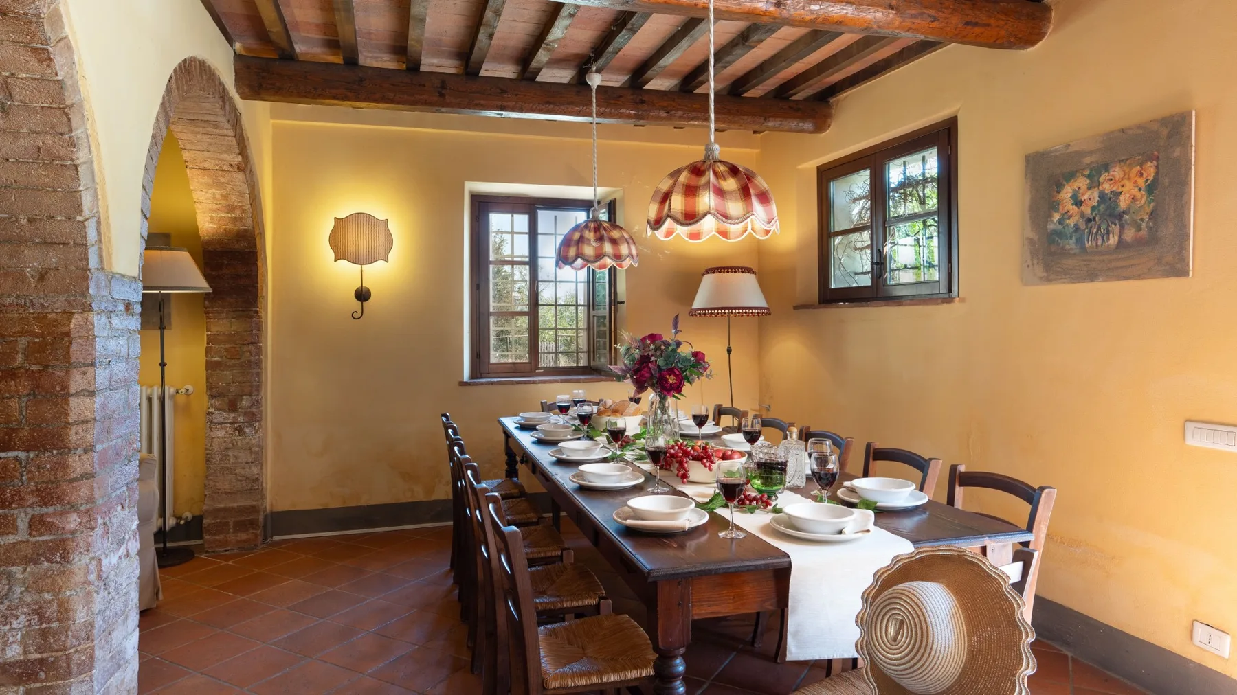 Un comedor con una mesa larga puesta con platos y flores.