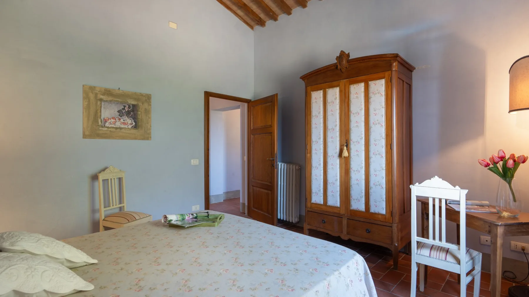 Un dormitorio con una cama grande, un armario de madera y una puerta abierta.
